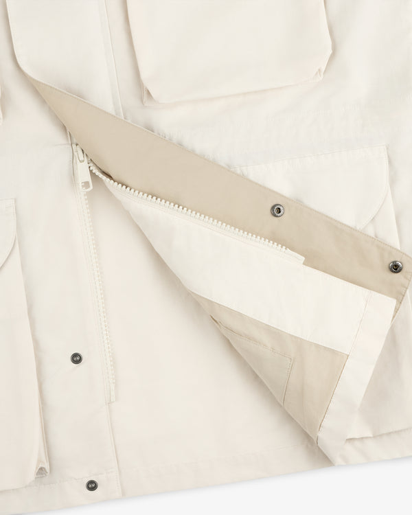 Close-up of the Lightweight Barn Jacket in beige shows open zipper, snap buttons, and large front pockets.