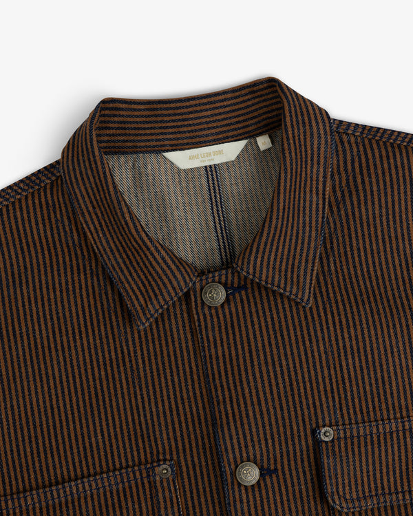 Hickory Stripe Denim Trucker Jacket with collar, chest pockets, and button closures in brown and navy stripes, top view.