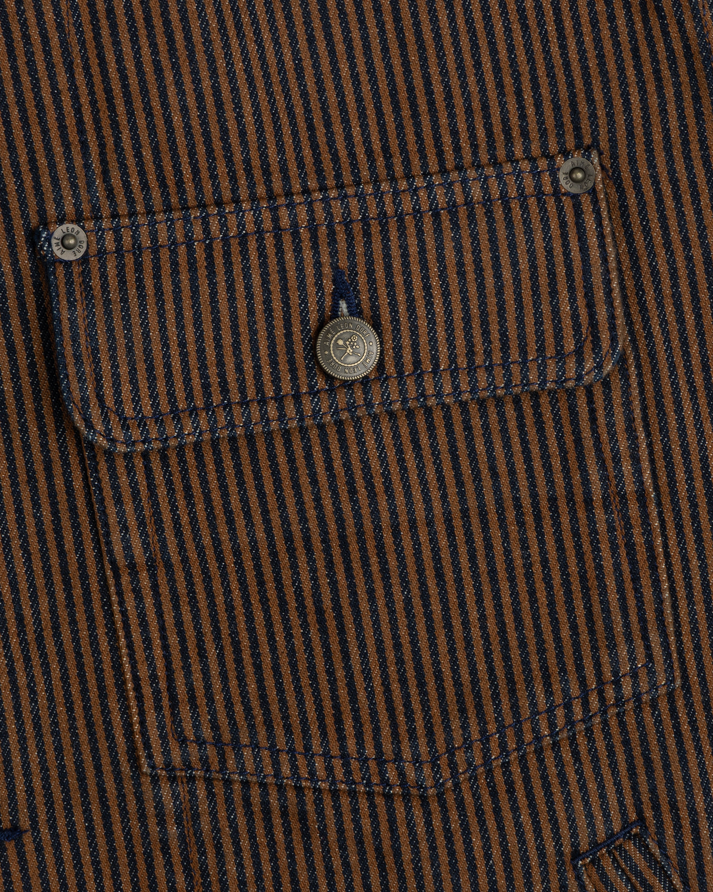 Hickory Stripe Denim Trucker Jacket with brown and navy stripes, pocket, and metal buttons on the garment.