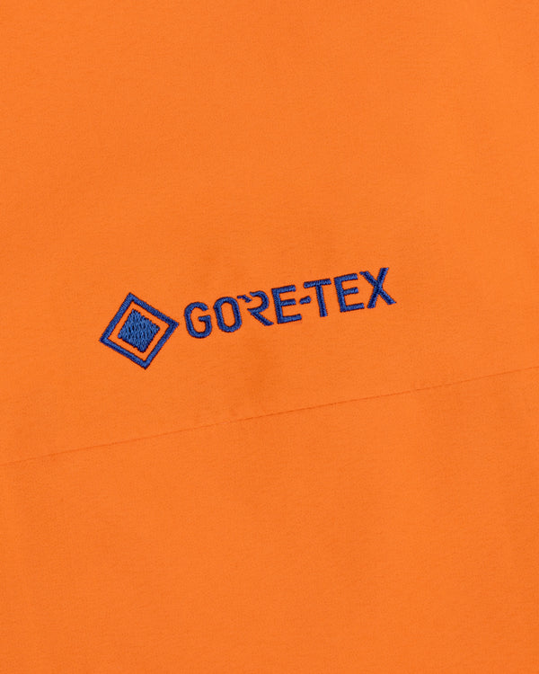 Mets GORE-TEX Rain Delay Jacket: Orange with blue embroidered GORE-TEX logo and geometric symbol on the surface.