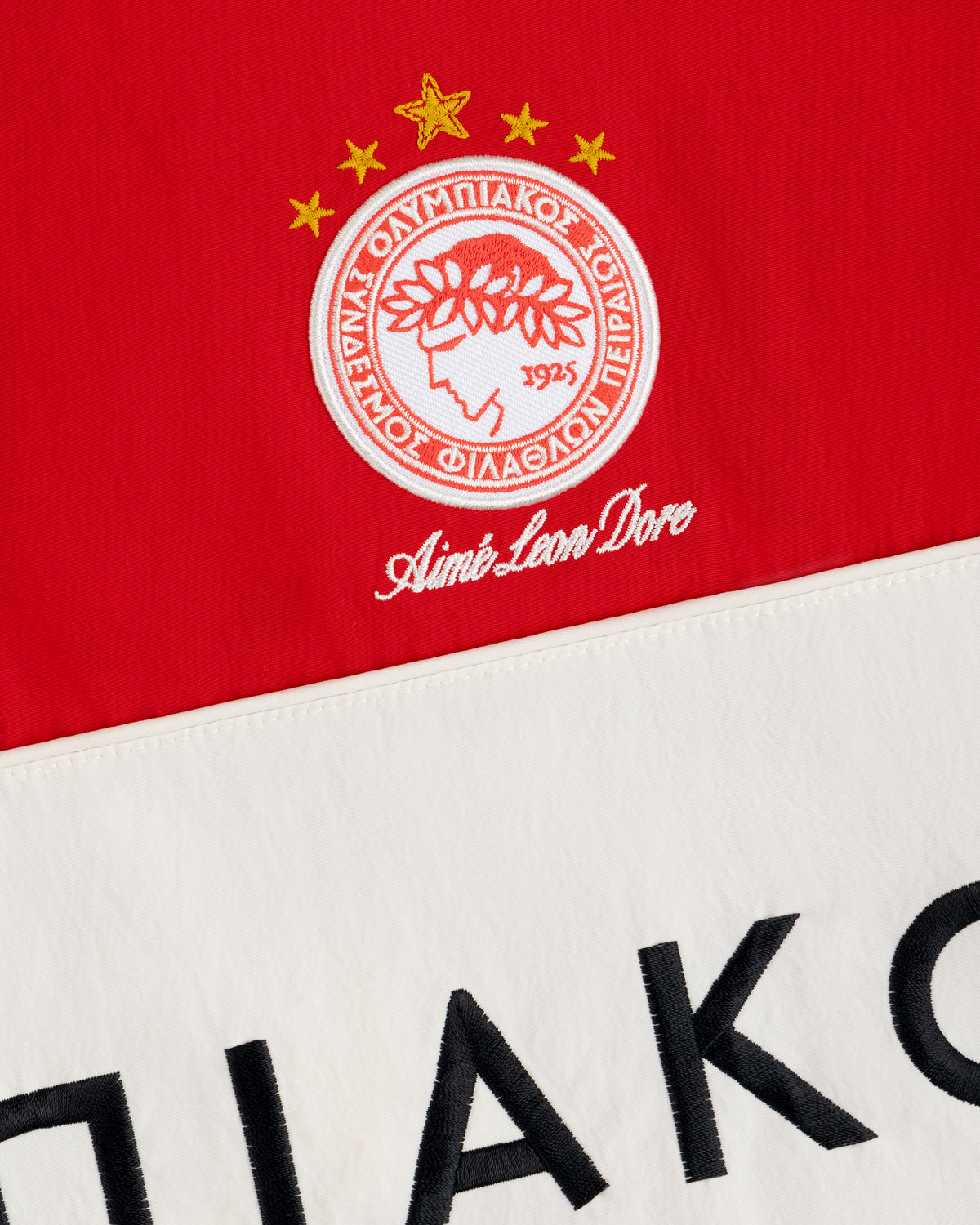 Red and off-white ALD / Olympiacos F.C. Nylon Quarter Zip Pullover featuring an embroidered crest with stars and text.