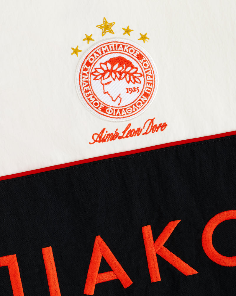 ALD / Olympiacos F.C. Nylon Quarter Zip Pullover in white with an embroidered logo and red lettering on a black panel.