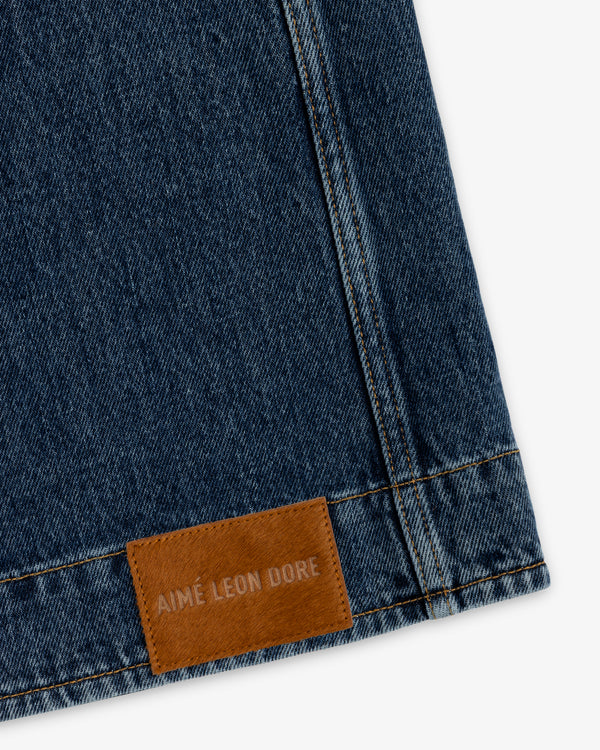 Denim Chore Coat in dark blue denim with gold stitching and a brown leather patch embossed with Aimé Leon Dore.