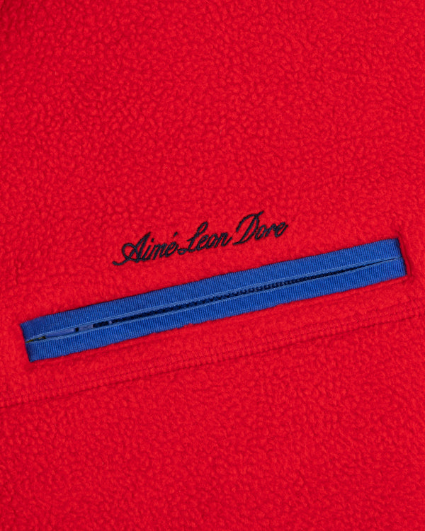 Script Fleece Half Zip Pullover in red fleece with a blue zippered chest pocket featuring embroidered cursive text.