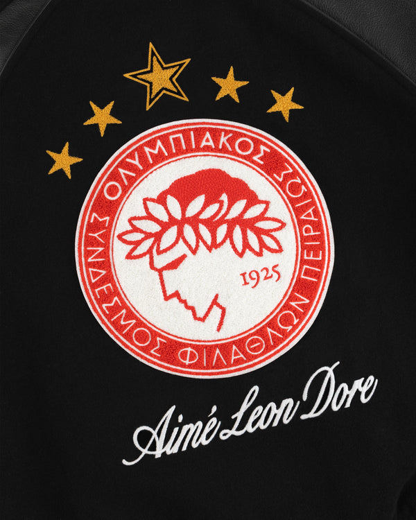 Embroidered red and white sports emblem above the brand name on a black ALD / Olympiacos F.C. Team Leather Jacket.