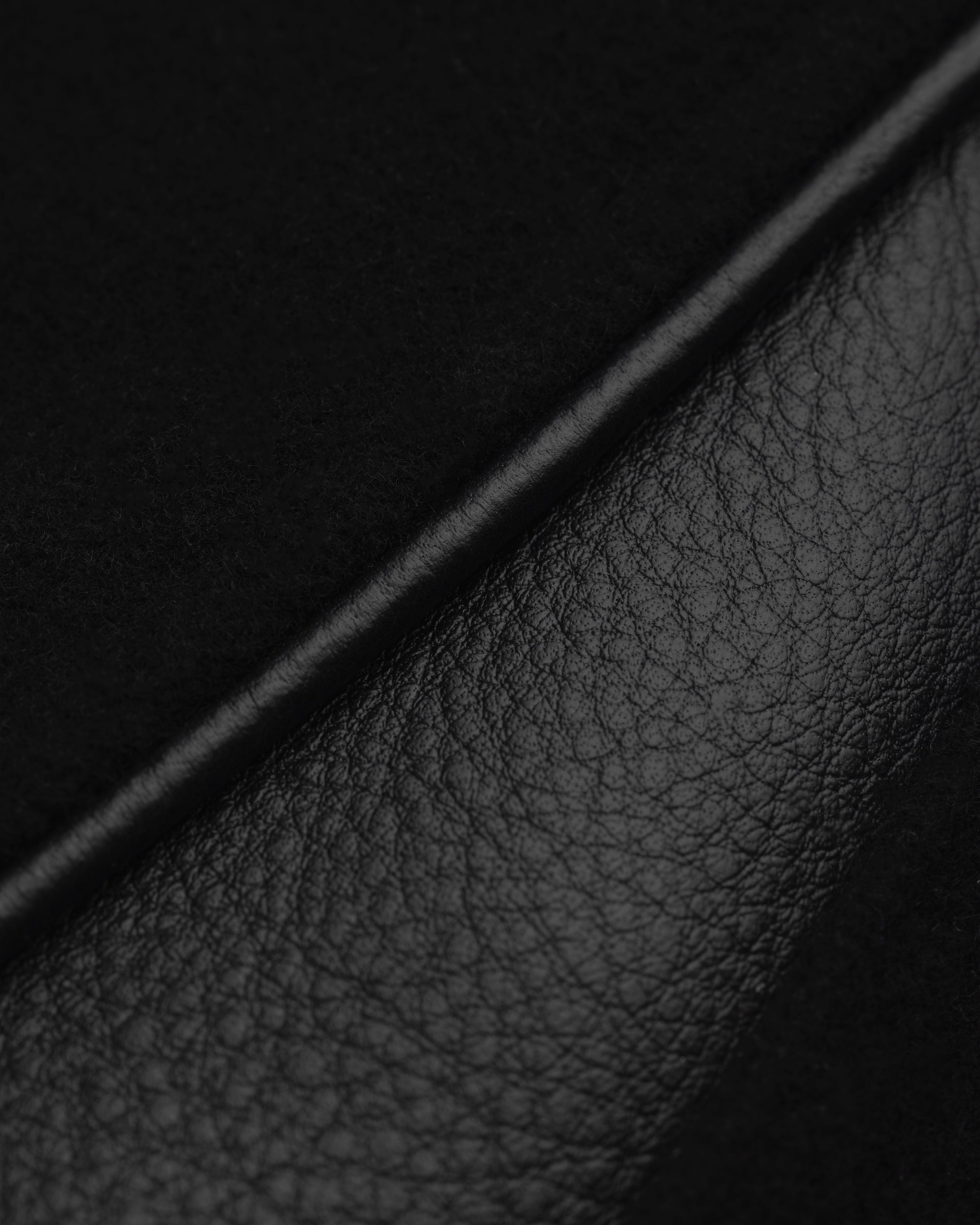 Close-up of the ALD / Olympiacos F.C. Team Leather Jacket in black leather and suede panels separated by a piped seam.