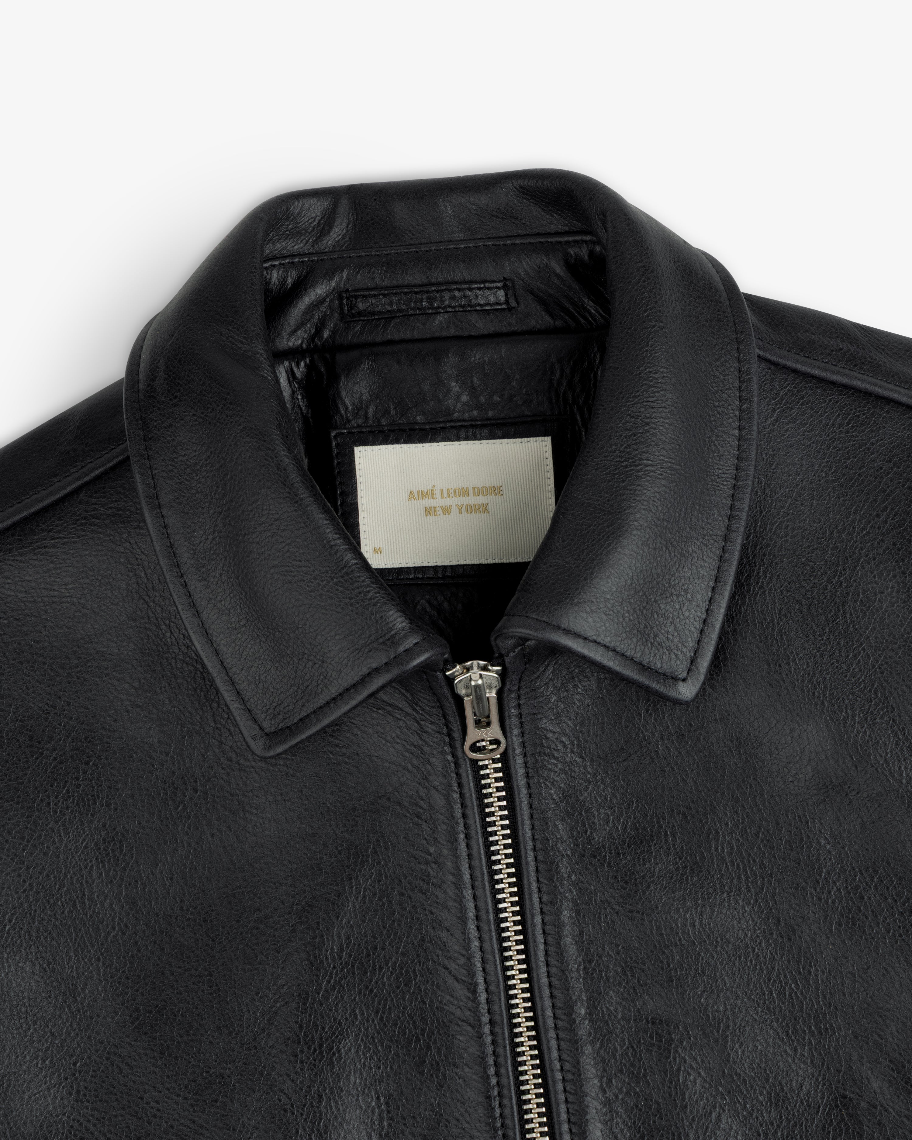 Close-up of a black Napa Leather Bomber Jacket featuring a front zipper and a white interior collar label.