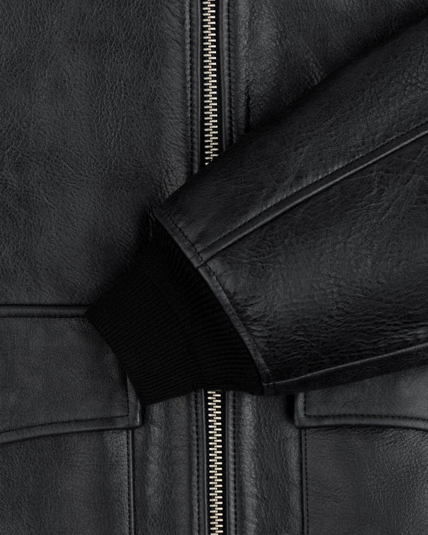 Close-up of a black Napa Leather Bomber Jacket featuring a metal zipper and a ribbed knit cuff.