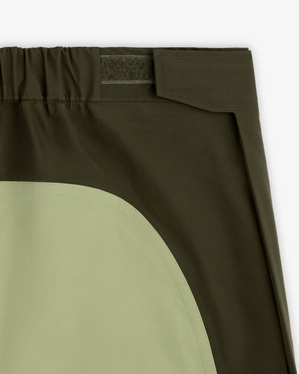Close-up of ALD / The North Face GORE-TEX Pant: dark green, elastic waistband, Velcro closure, light green pocket.