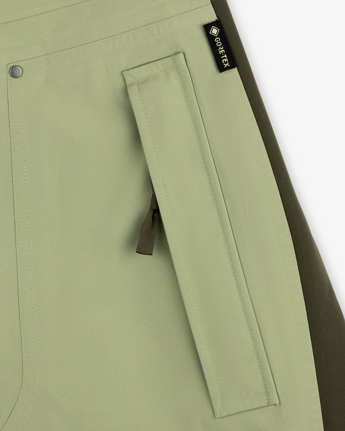 Close-up of a light green ALD / The North Face GORE-TEX Pant pocket with zipper and black fabric tag.