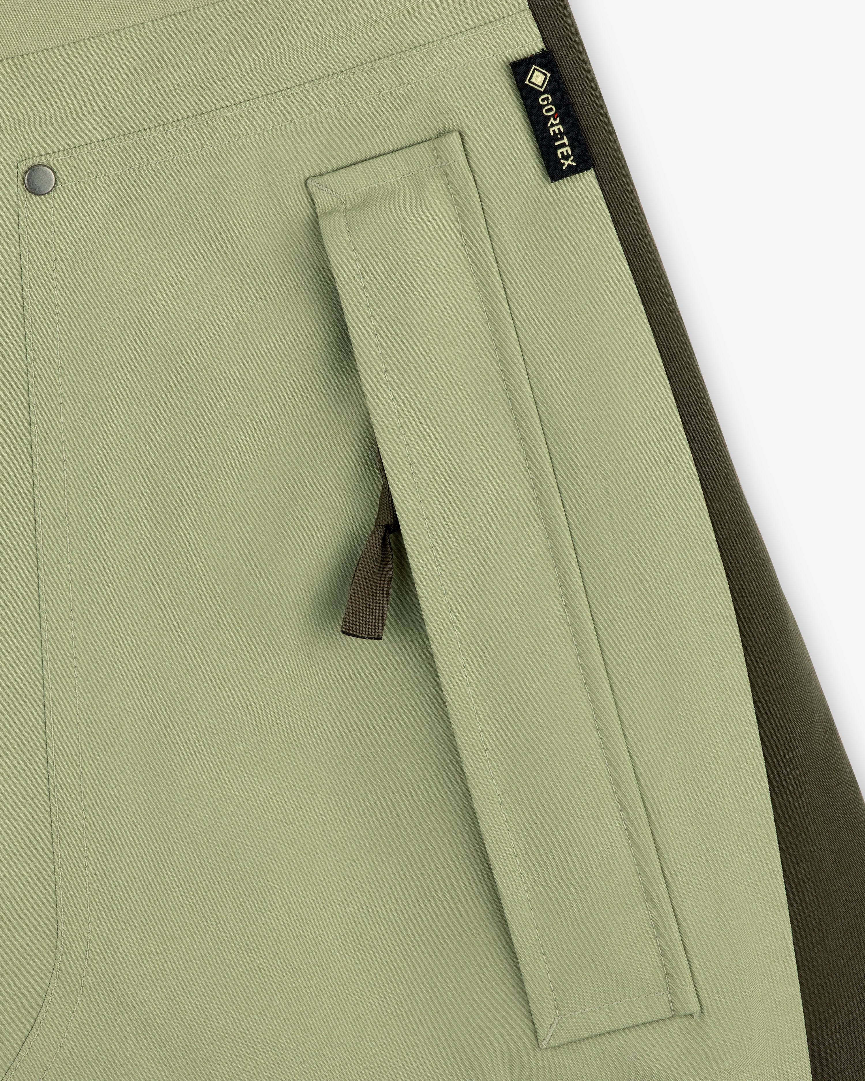 Close-up of a light green ALD / The North Face GORE-TEX Pant pocket with zipper and black fabric tag.