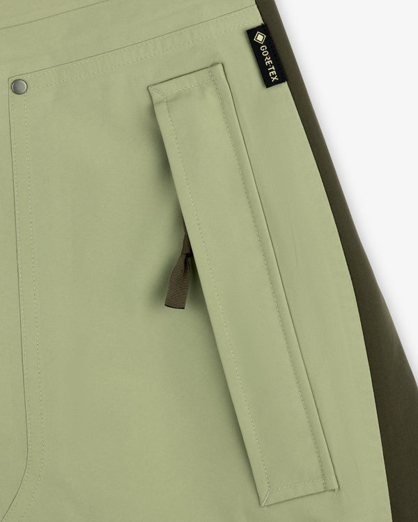 Close-up of a light green ALD / The North Face GORE-TEX Pant pocket with zipper and black fabric tag.