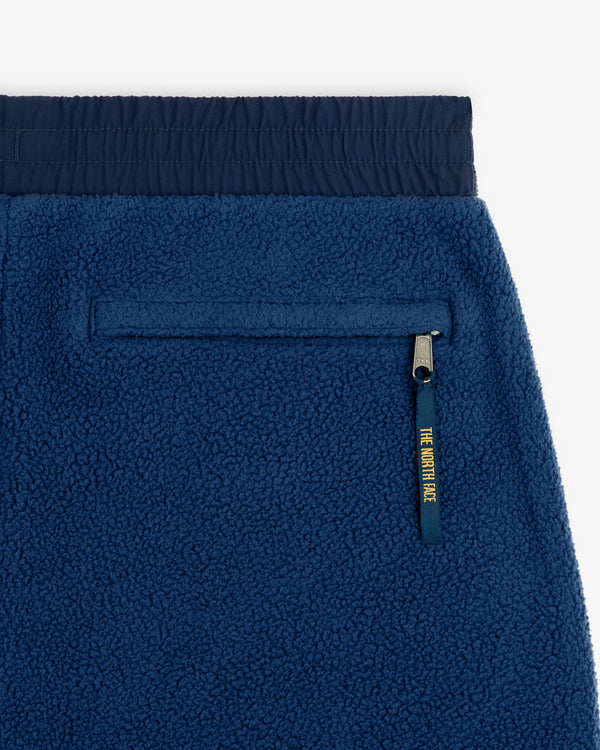 Close-up of ALD / The North Face Denali Fleece Pant: blue fleece, zip pocket with yellow pull tab, elastic waistband.