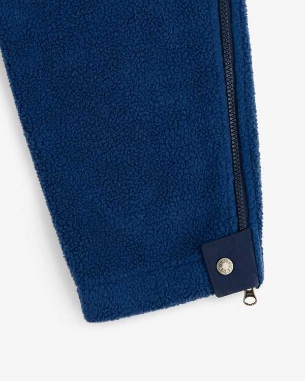 ALD / The North Face Denali Fleece Pant in blue with navy zipper, metal snap hem, shown on white background.