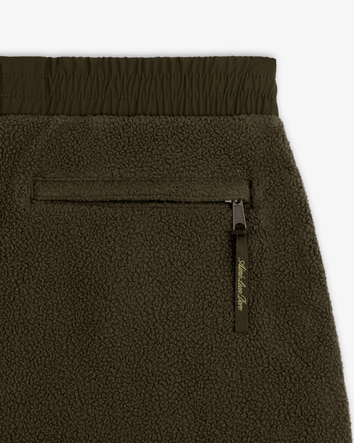 Close-up of ALD / The North Face Denali Fleece Pant in olive green, highlighting zip pocket, elastic waist, and texture.