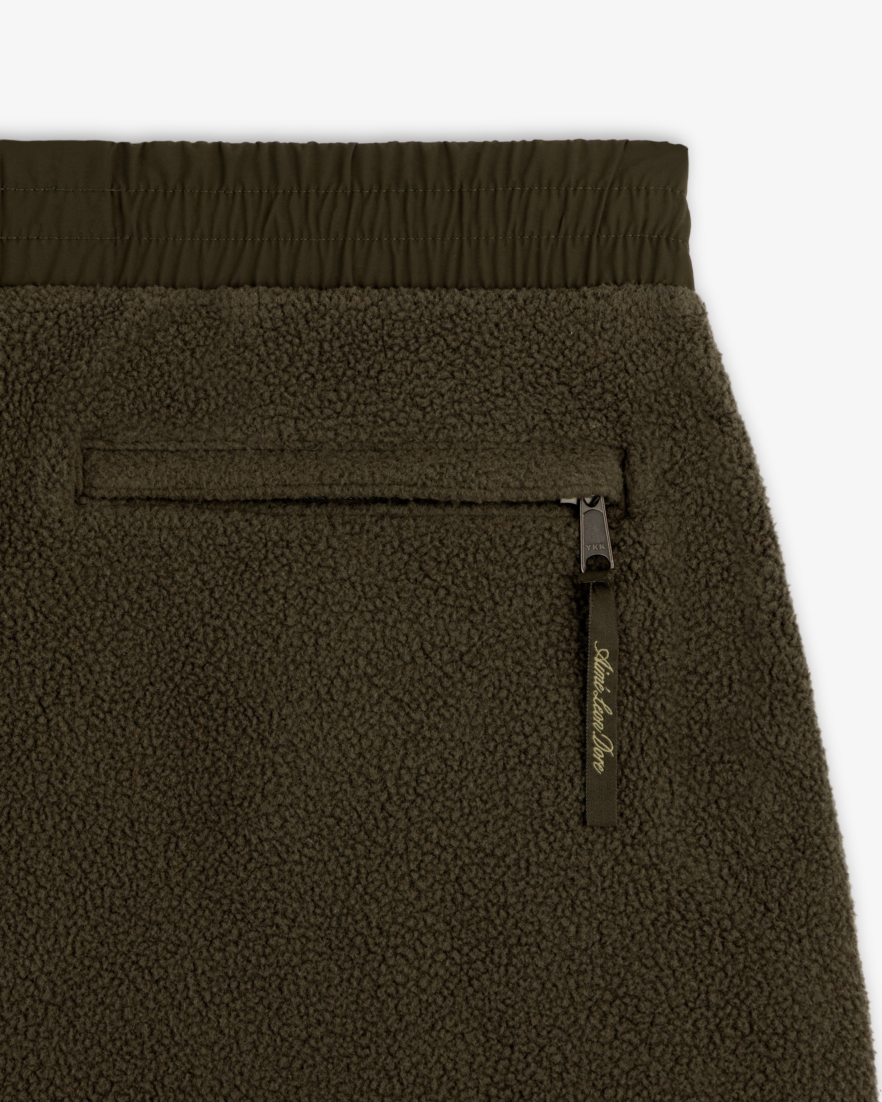 Close-up of ALD / The North Face Denali Fleece Pant in olive green, highlighting zip pocket, elastic waist, and texture.