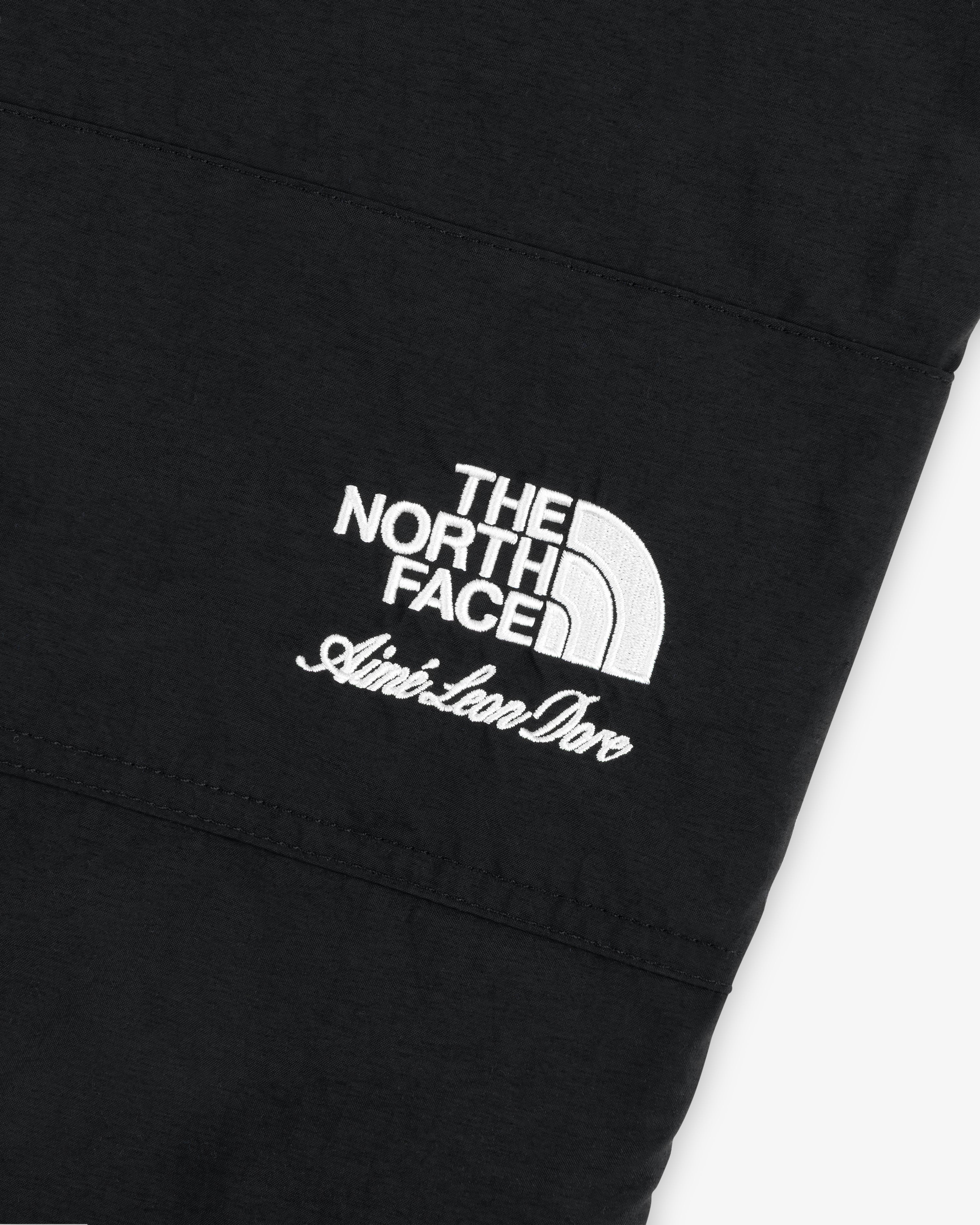 Black nylon Denali pant with white The North Face logo above Aime Leon Dore cursive embroidery.