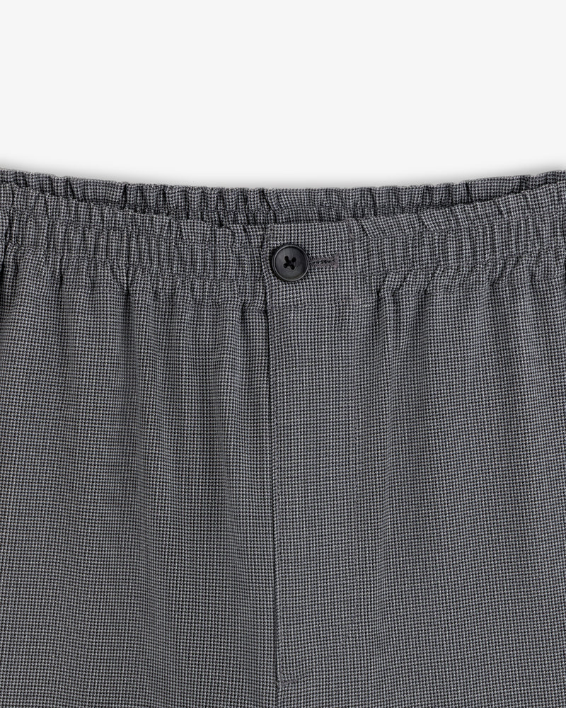 Close-up of the waistband on the Houndstooth Elasticated Waist Trouser with an elastic band and black button detail.