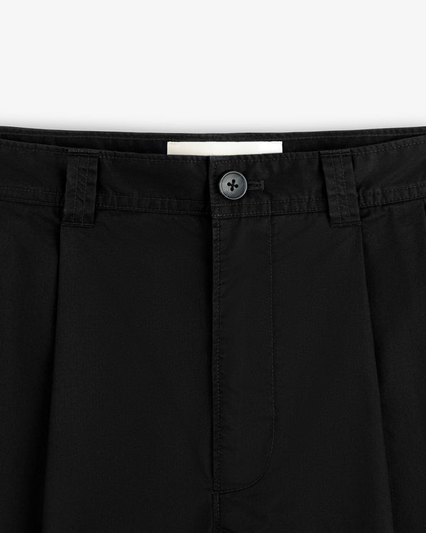 Close-up of the waistband and button of Double Pleated Officer Pant, featuring belt loops, pleats, and stitching.