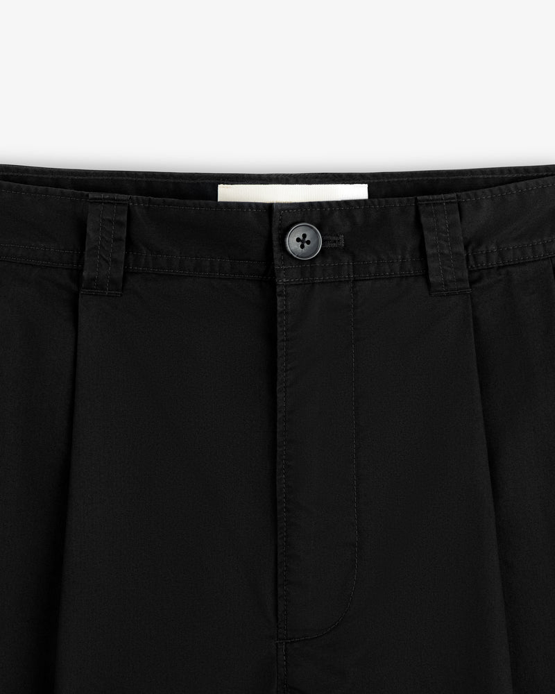 Close-up of the waistband and button of Double Pleated Officer Pant, featuring belt loops, pleats, and stitching.
