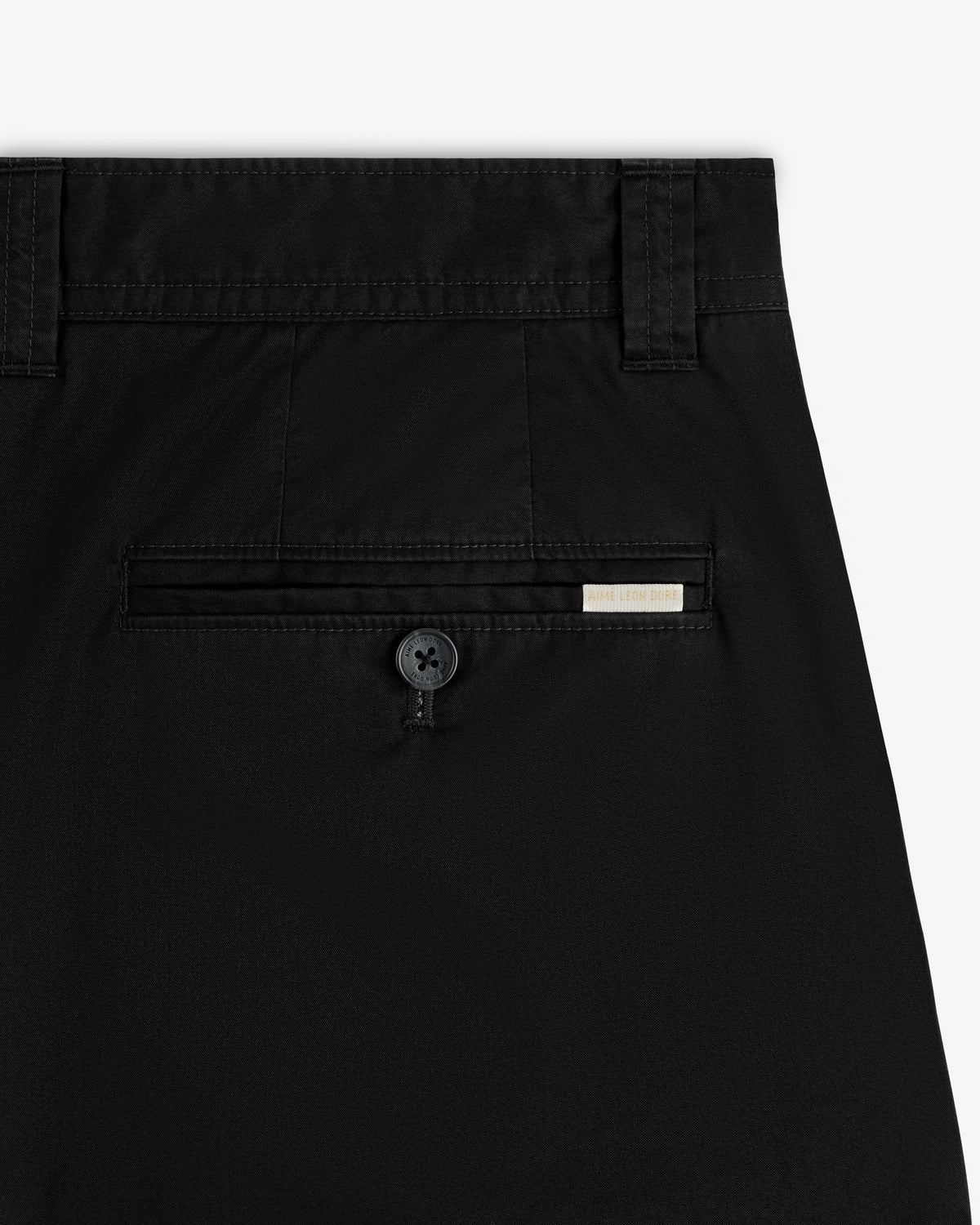 Close-up of the back pocket on Double Pleated Officer Pant, featuring a button and a small rectangular tag above it.