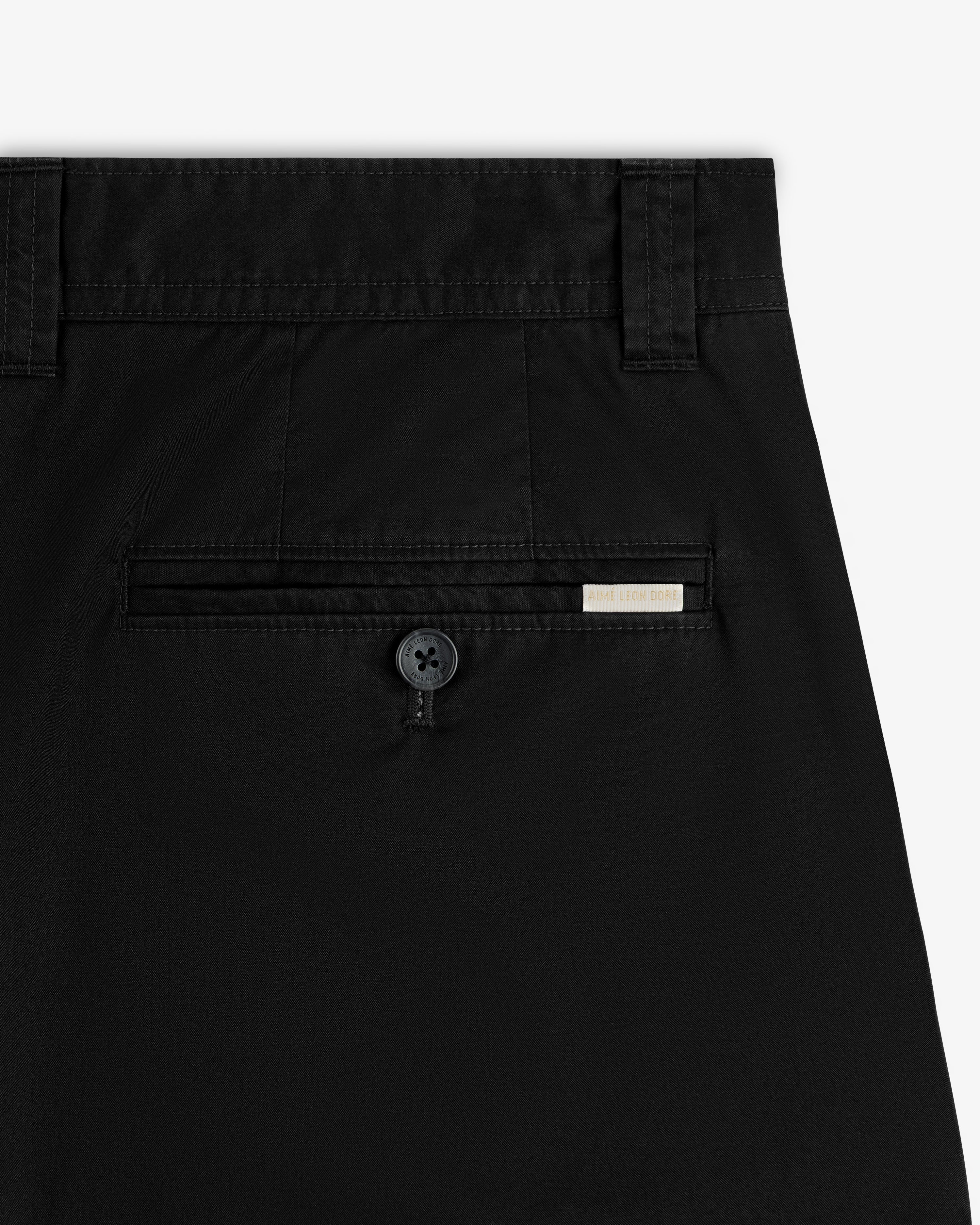 Close-up of the back pocket on Double Pleated Officer Pant, featuring a button and a small rectangular tag above it.