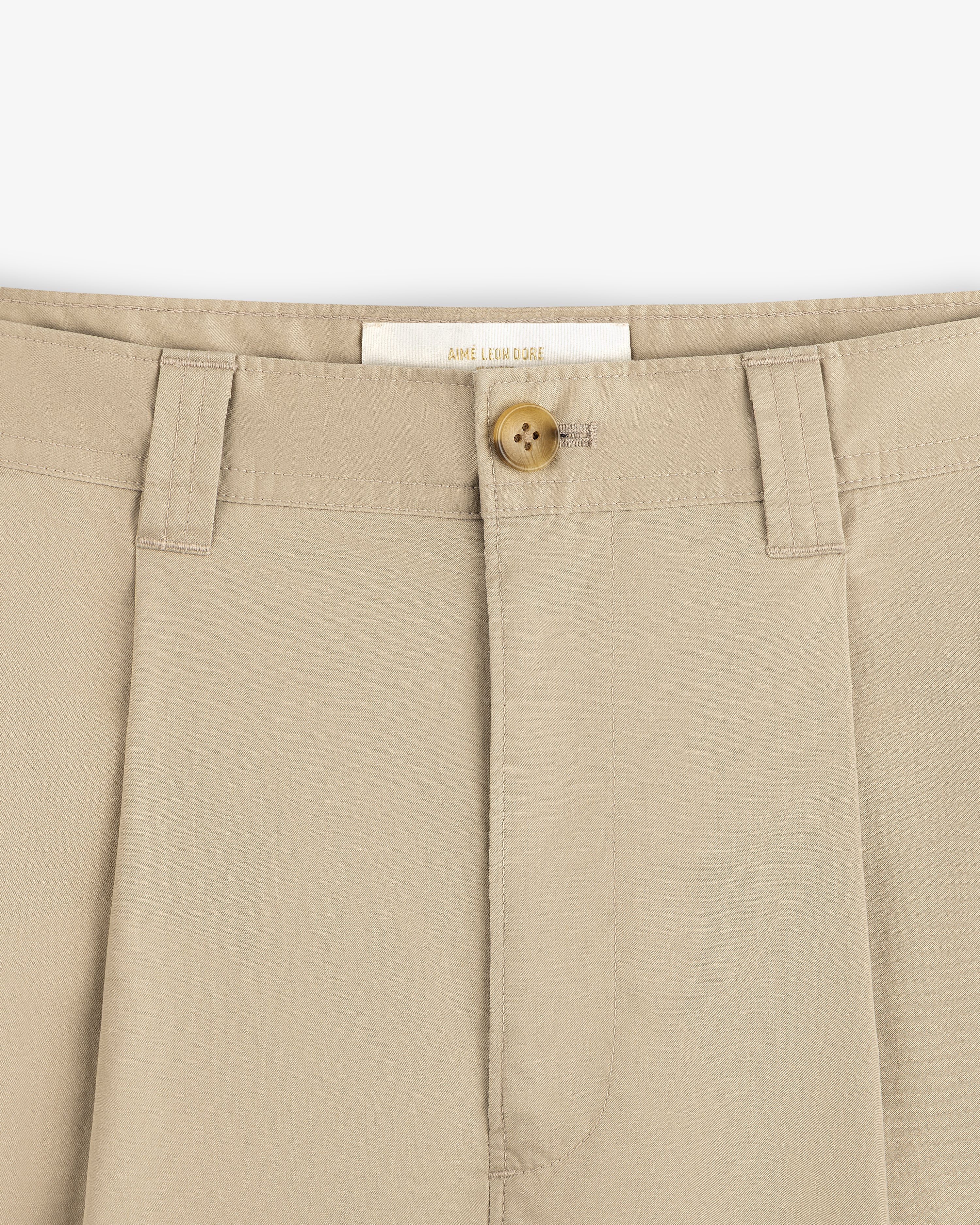 Close-up of Double Pleated Officer Pant waistband with belt loops, tan button, and visible Aimé Leon Dore label.