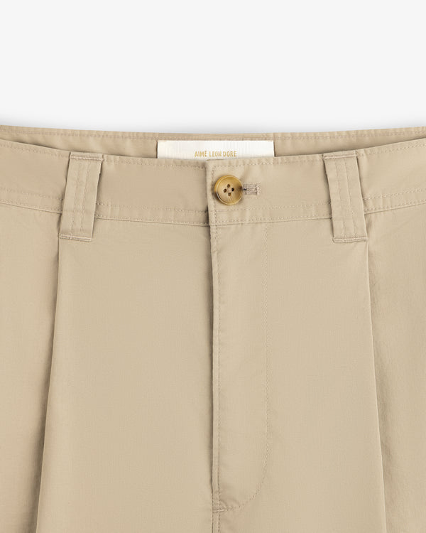 Close-up of Double Pleated Officer Pant waistband with belt loops, tan button, and visible Aimé Leon Dore label.