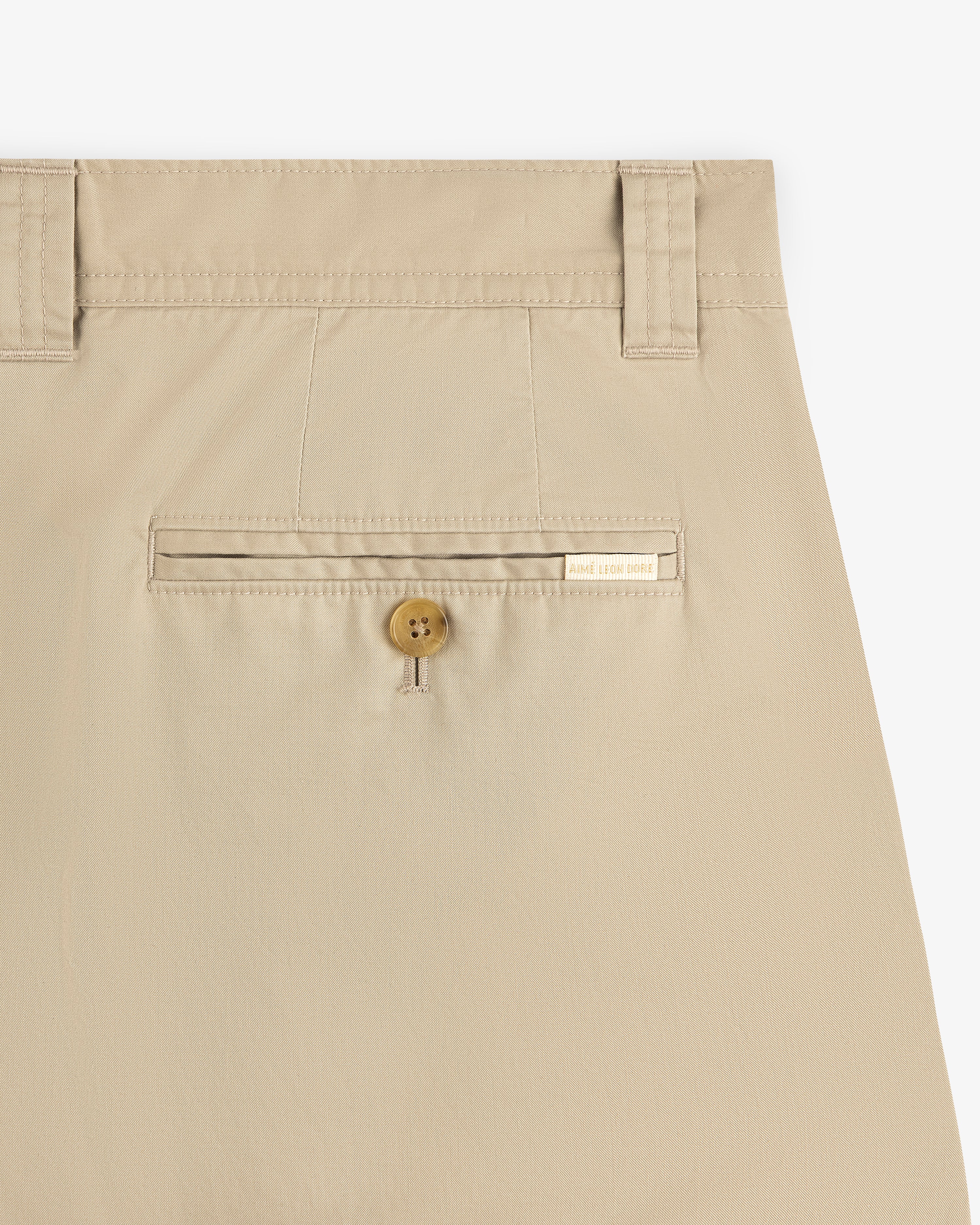 Double Pleated Officer Pant in beige with belt loops, buttoned back pocket, and a label above the pocket.