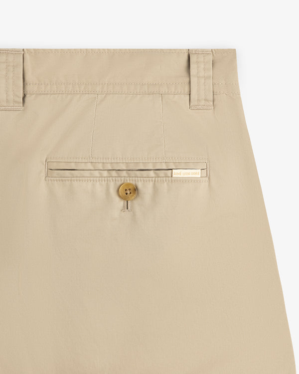 Double Pleated Officer Pant in beige with belt loops, buttoned back pocket, and a label above the pocket.
