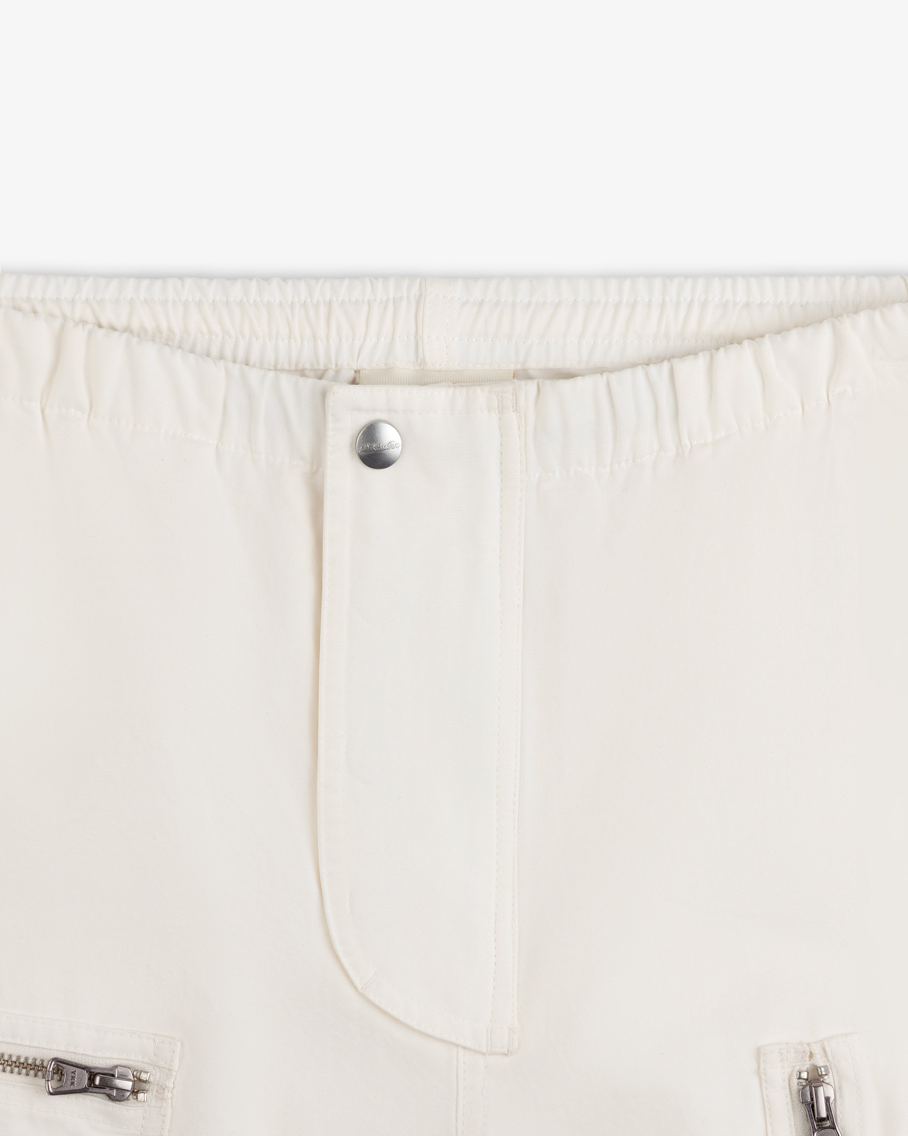 Garment Washed Aviator Pants in off-white with an elastic waistband, single silver button, and zippered pockets.