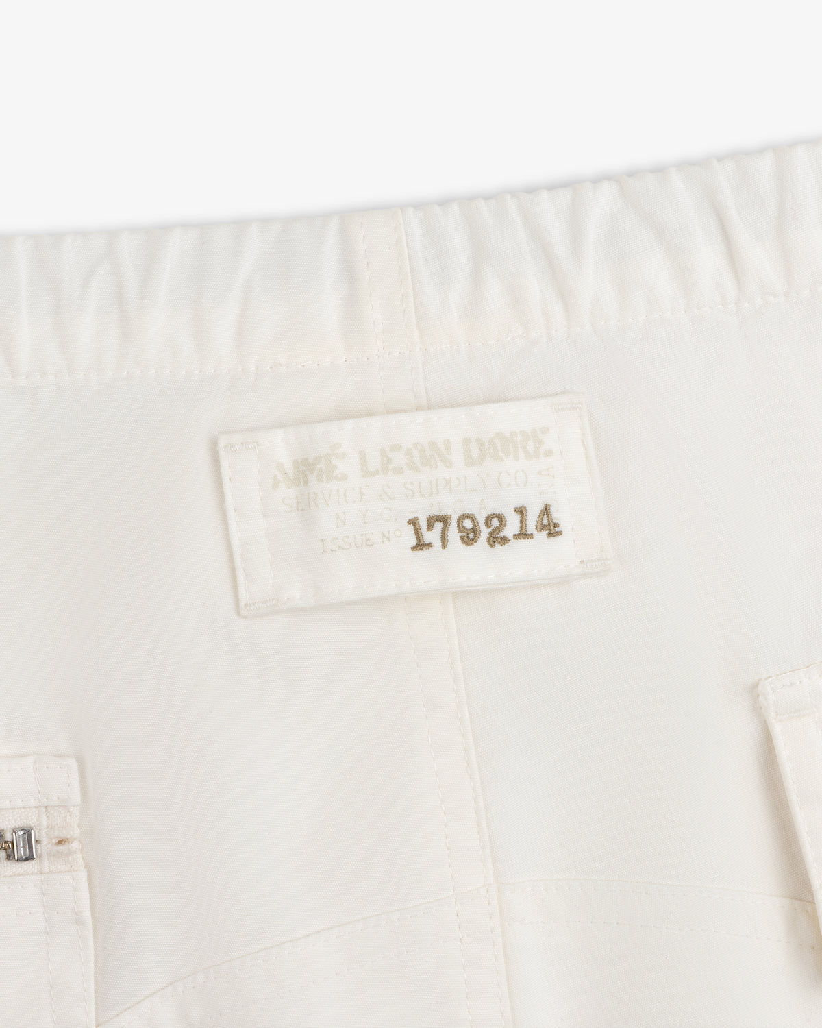 Off-white Garment Washed Aviator Pant featuring a rectangular patch with Aimé Leon Dore Service & Supply Co. Issue No 179214.