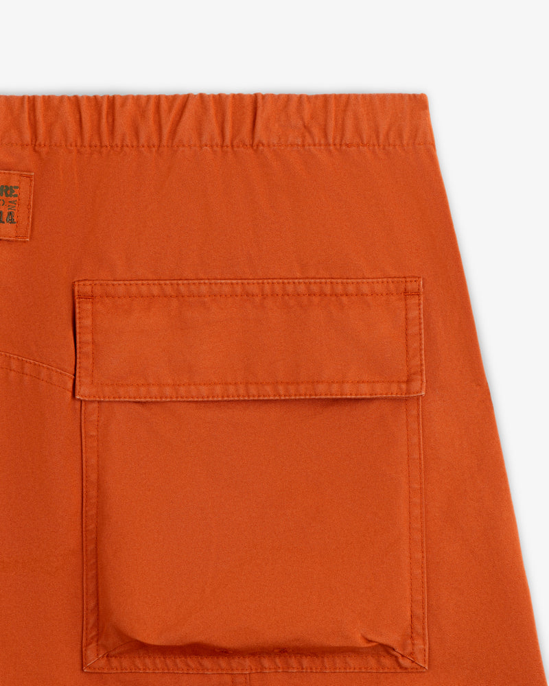 Close-up of an orange Garment Washed Aviator Pant leg featuring a large patch pocket and an elastic waistband.
