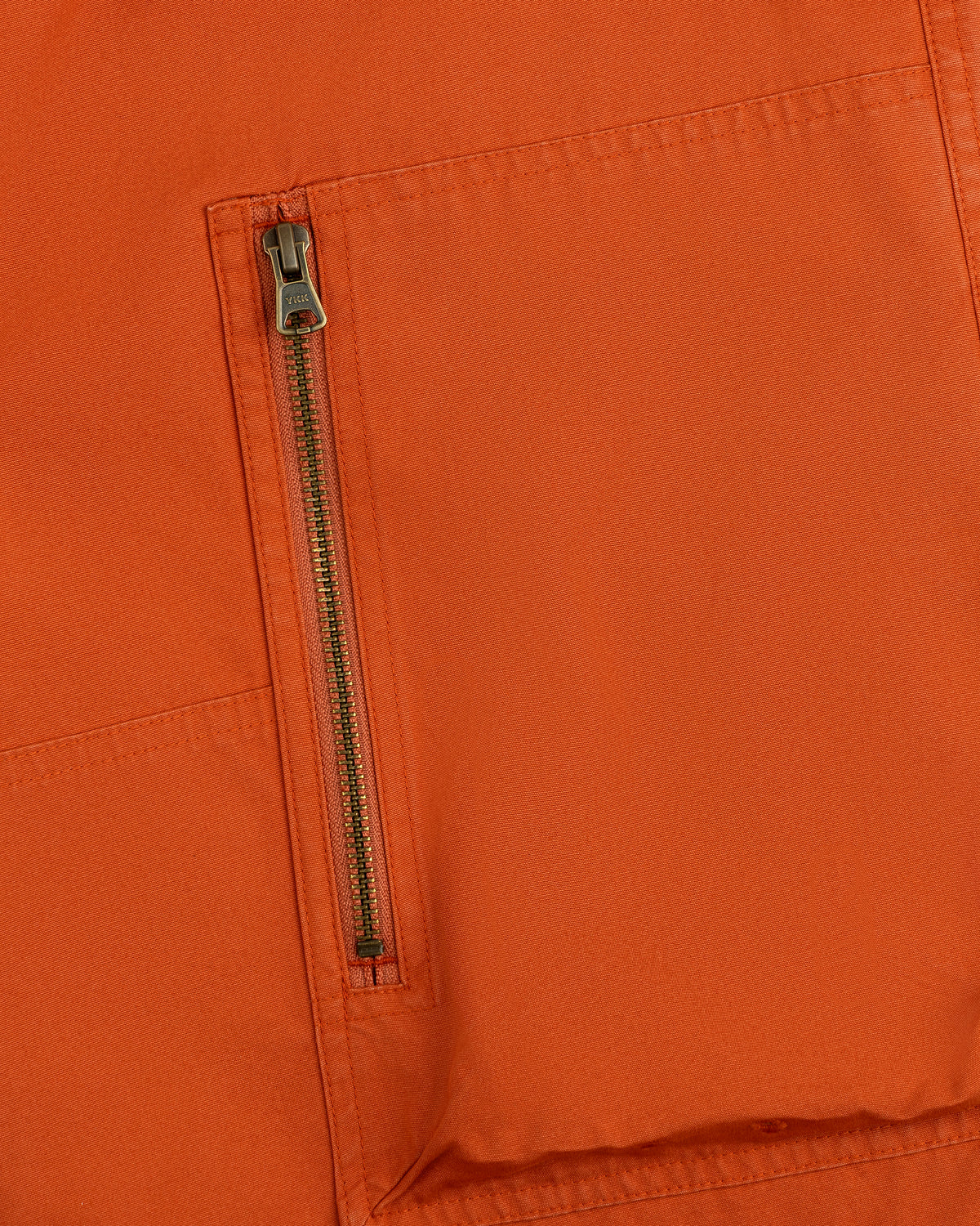 Close-up of a vertical zipper pocket on the orange Garment Washed Aviator Pant.
