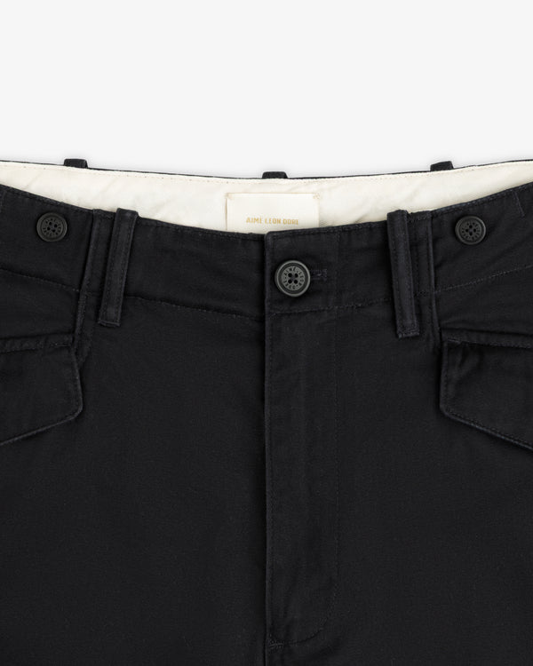 Close-up of the Fatigue Pant’s black waistband with two buttons, belt loops, and flap pockets on white background.