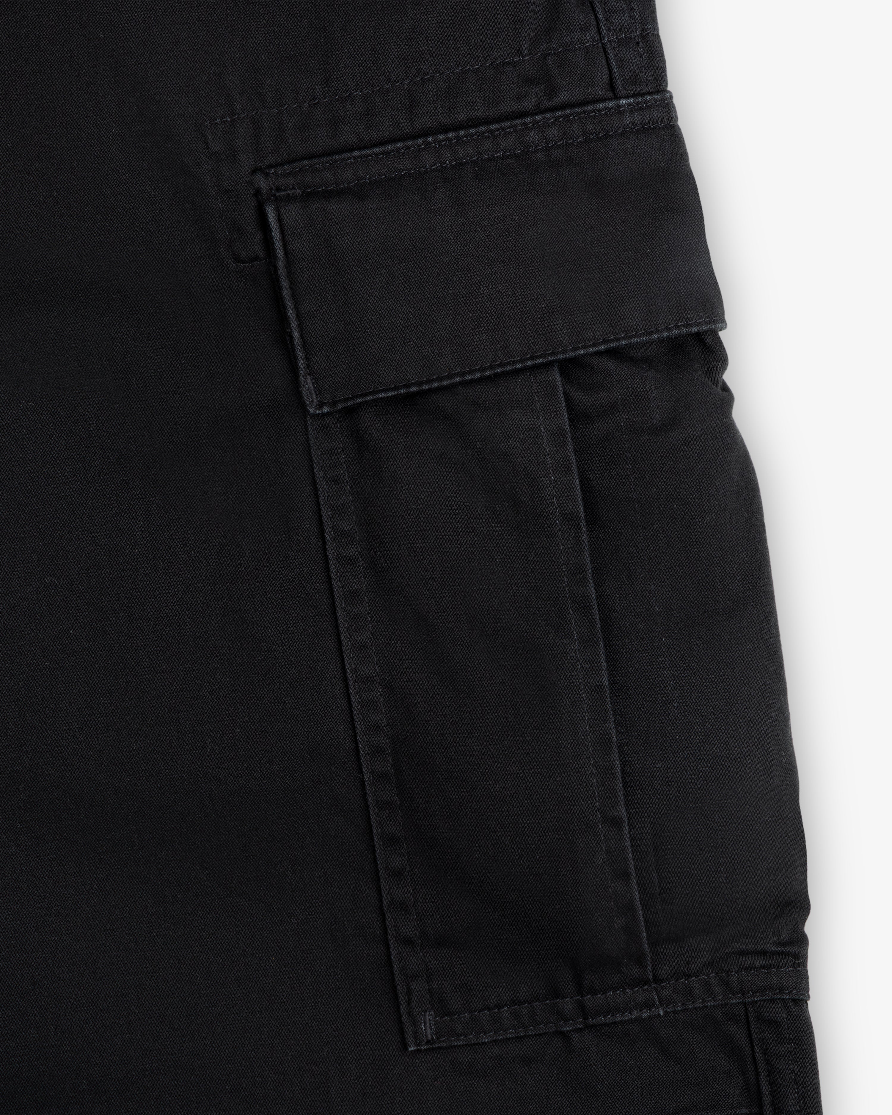 Close-up of the Fatigue Pant’s black cargo pocket, featuring a flap closure and visible stitching details.
