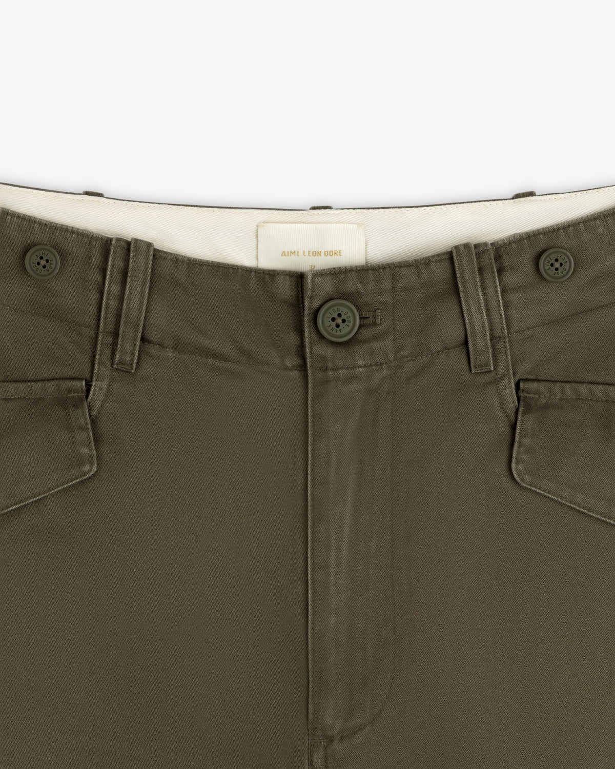 Close-up of Fatigue Pant in olive green, featuring button closure, front pockets, and a white waistband label.