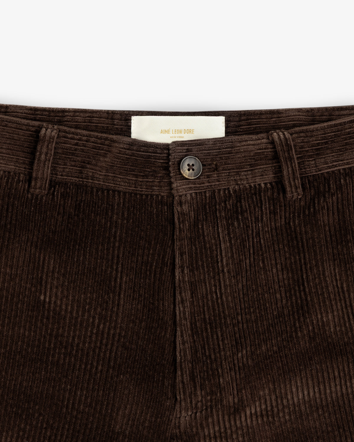Close-up of brown Corduroy Trouser featuring a button closure and a brand label at the waistband.