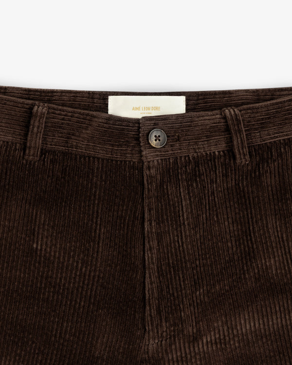 Close-up of brown Corduroy Trouser featuring a button closure and a brand label at the waistband.