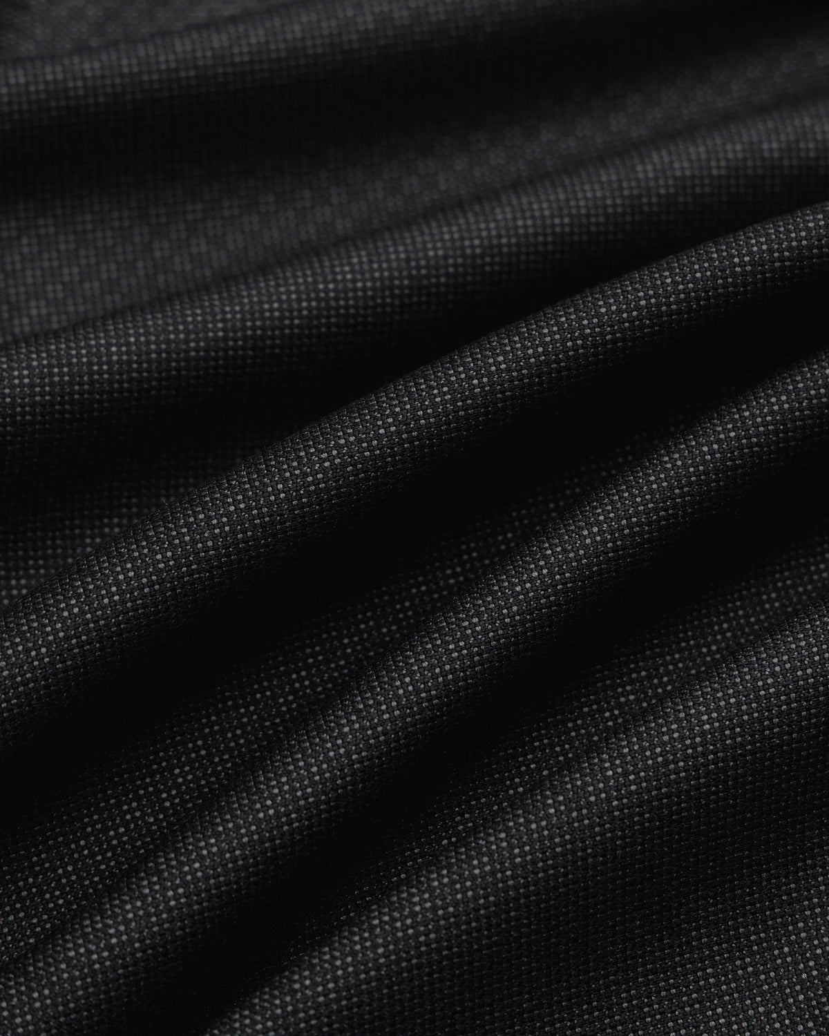 Close-up of draped black fabric with a fine textured weave for Double Pleated Wool Jacquard Suit Trouser.