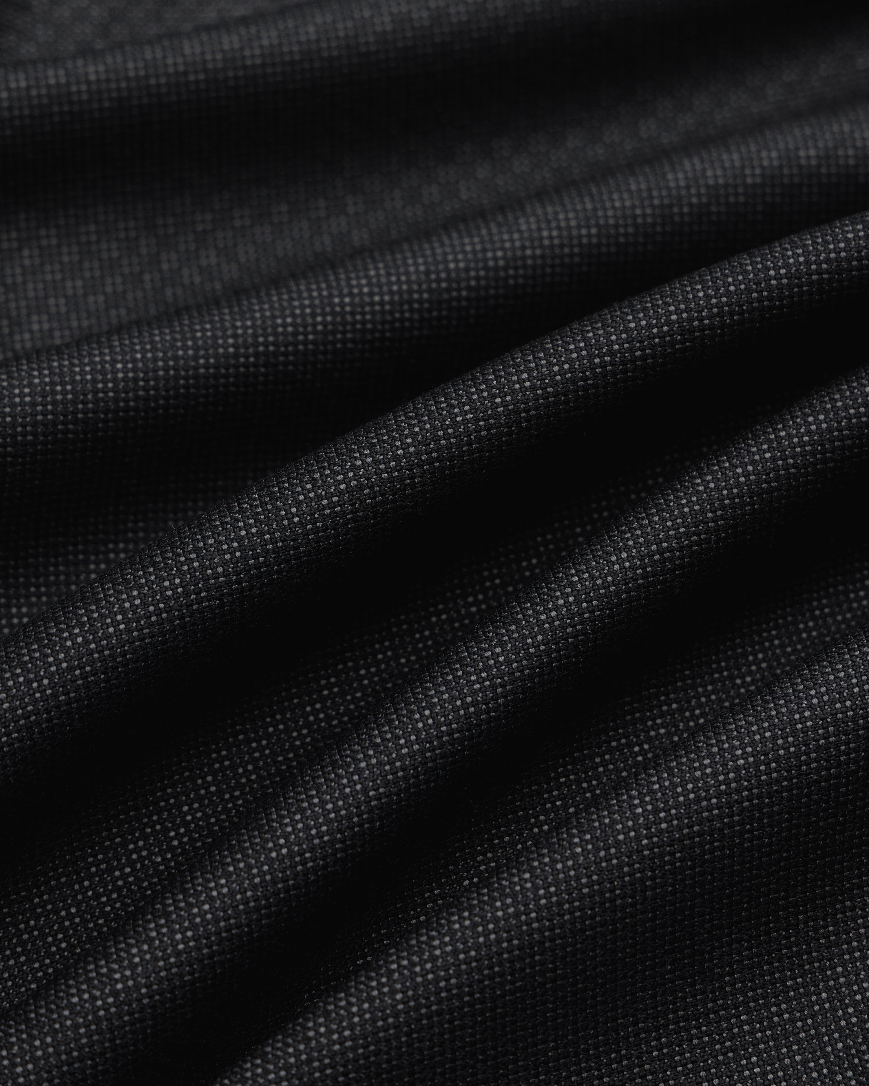 Close-up of draped black fabric with a fine textured weave for Double Pleated Wool Jacquard Suit Trouser.
