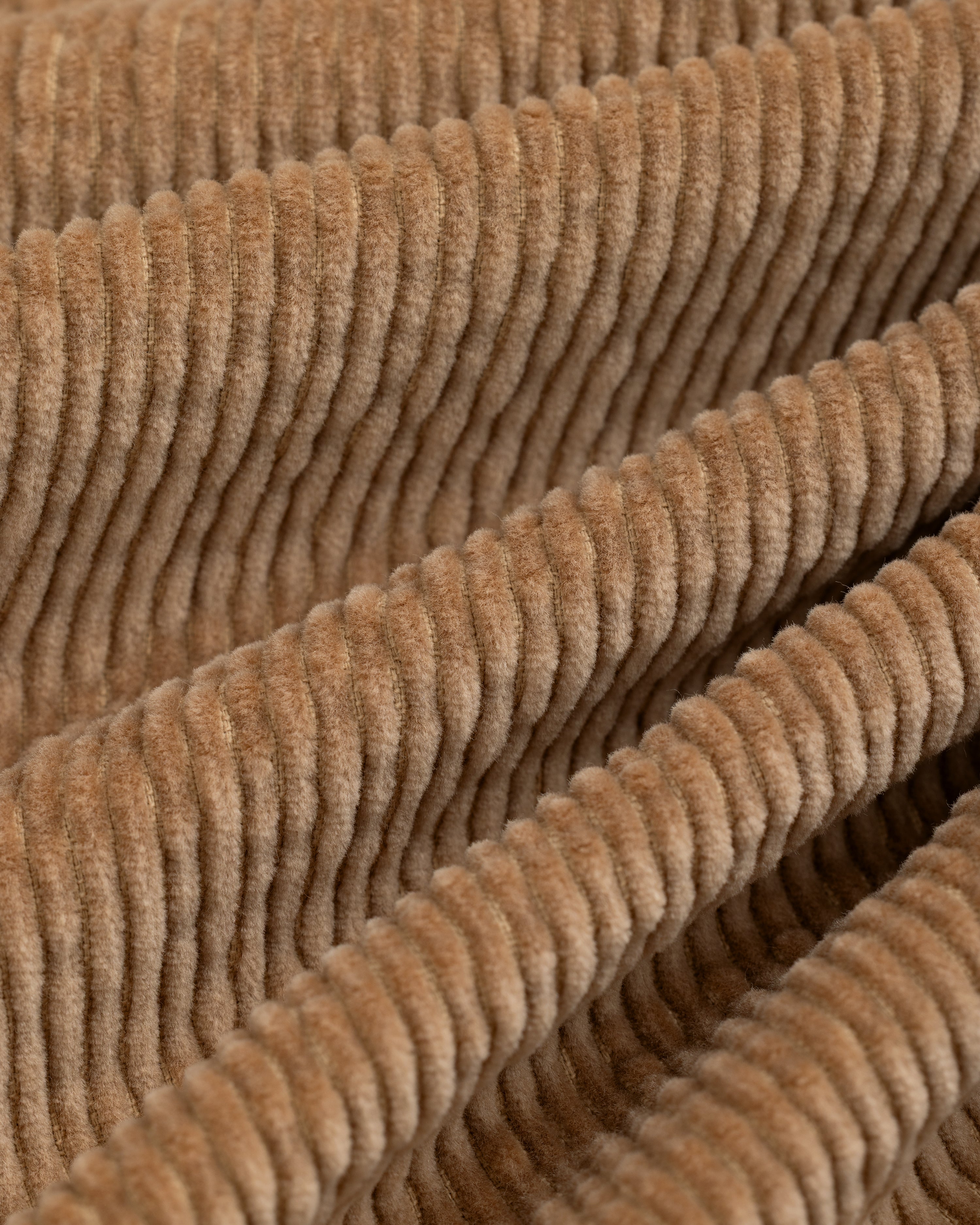 Close-up of tan Double Pleated Corduroy Trouser fabric featuring vertical ridges and folds.
