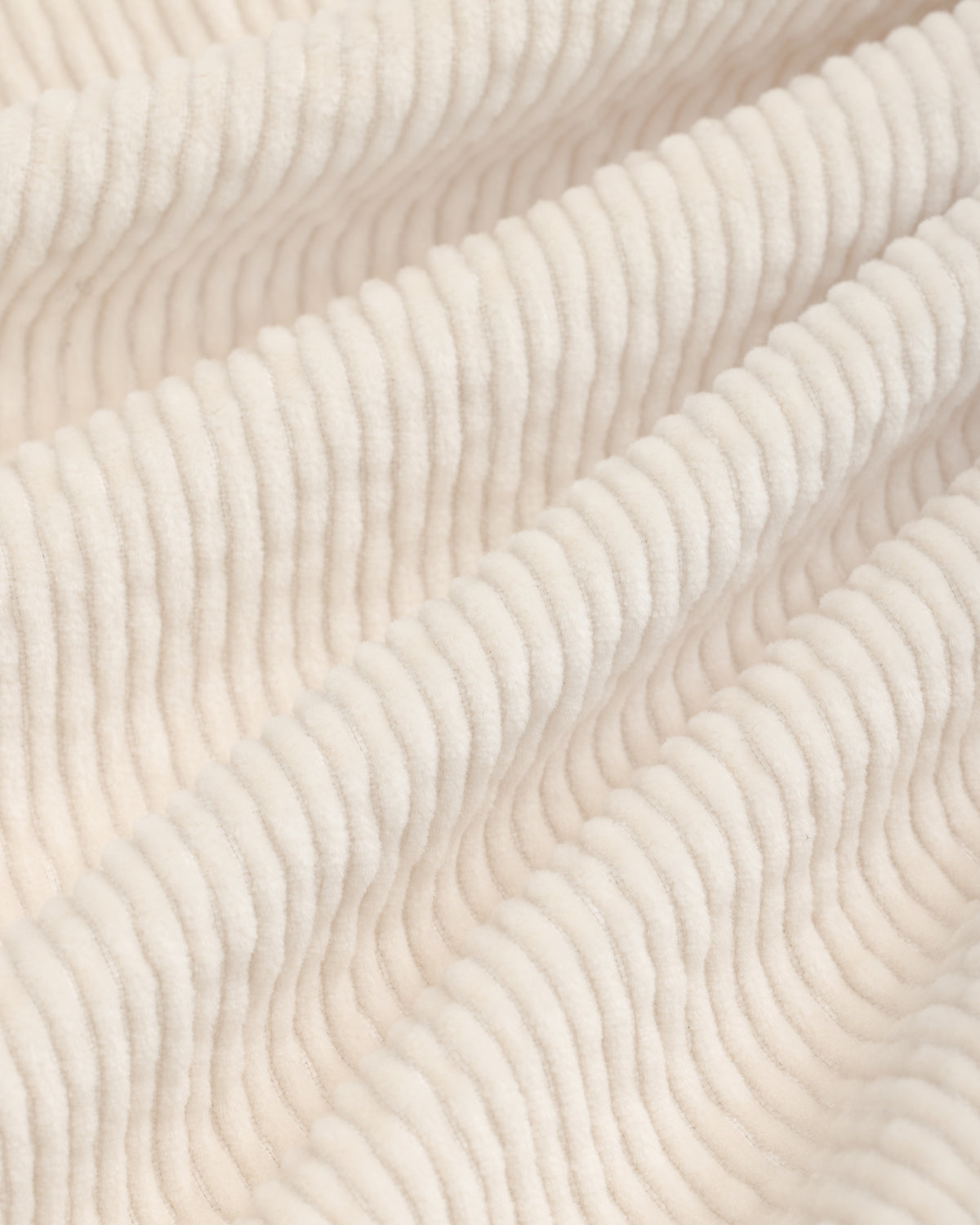 Close-up of beige Double Pleated Corduroy Trouser fabric with vertical ridges in soft folds.
