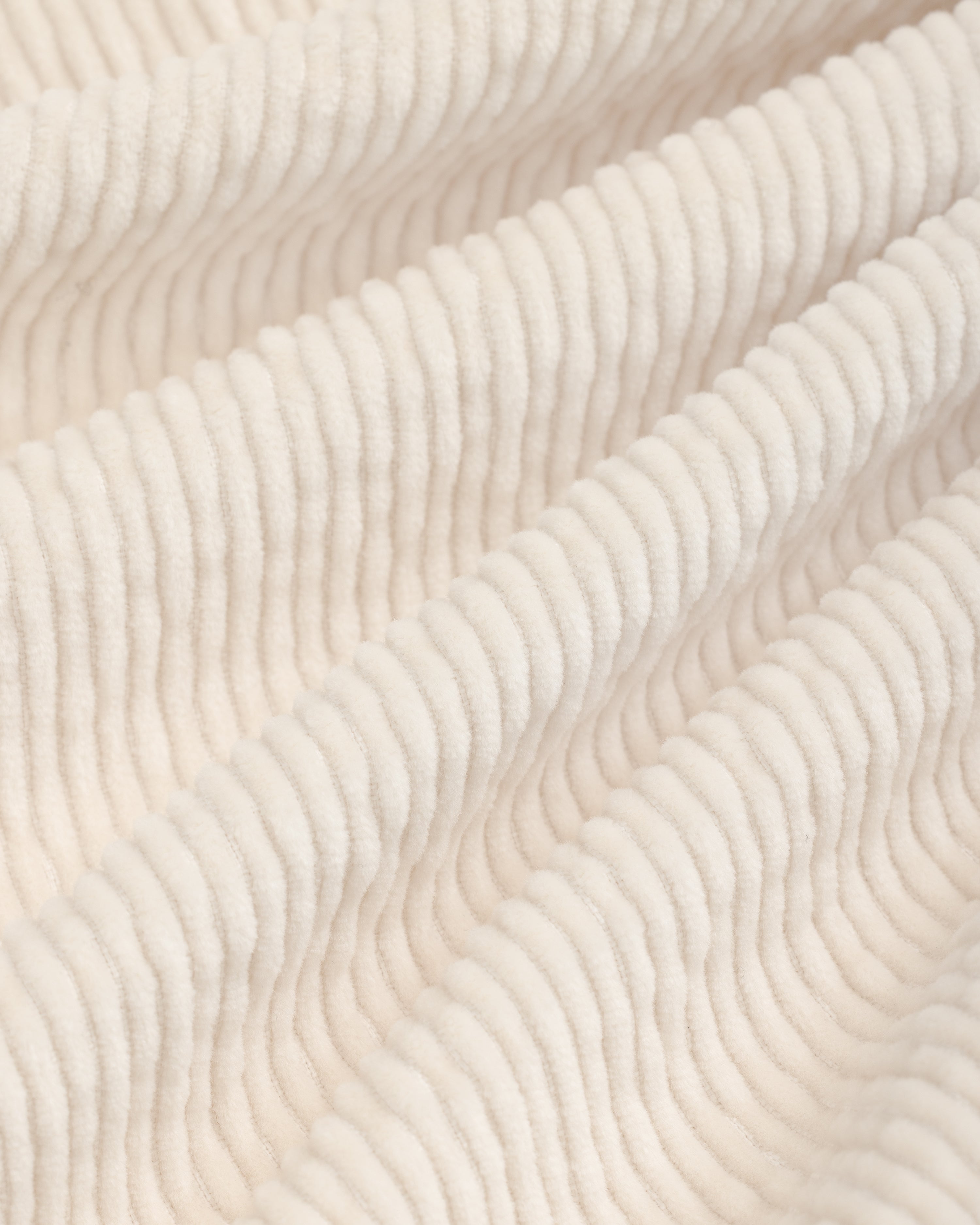 Close-up of beige Double Pleated Corduroy Trouser fabric with vertical ridges in soft folds.