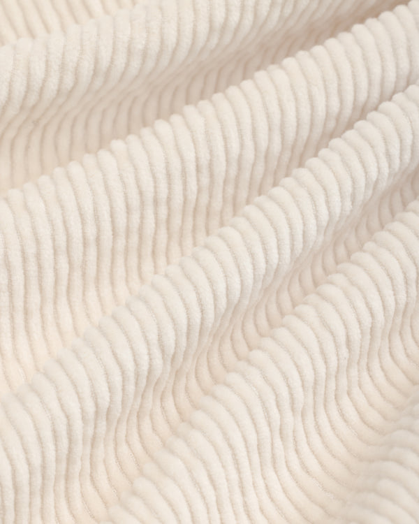 Close-up of beige Double Pleated Corduroy Trouser fabric with vertical ridges in soft folds.