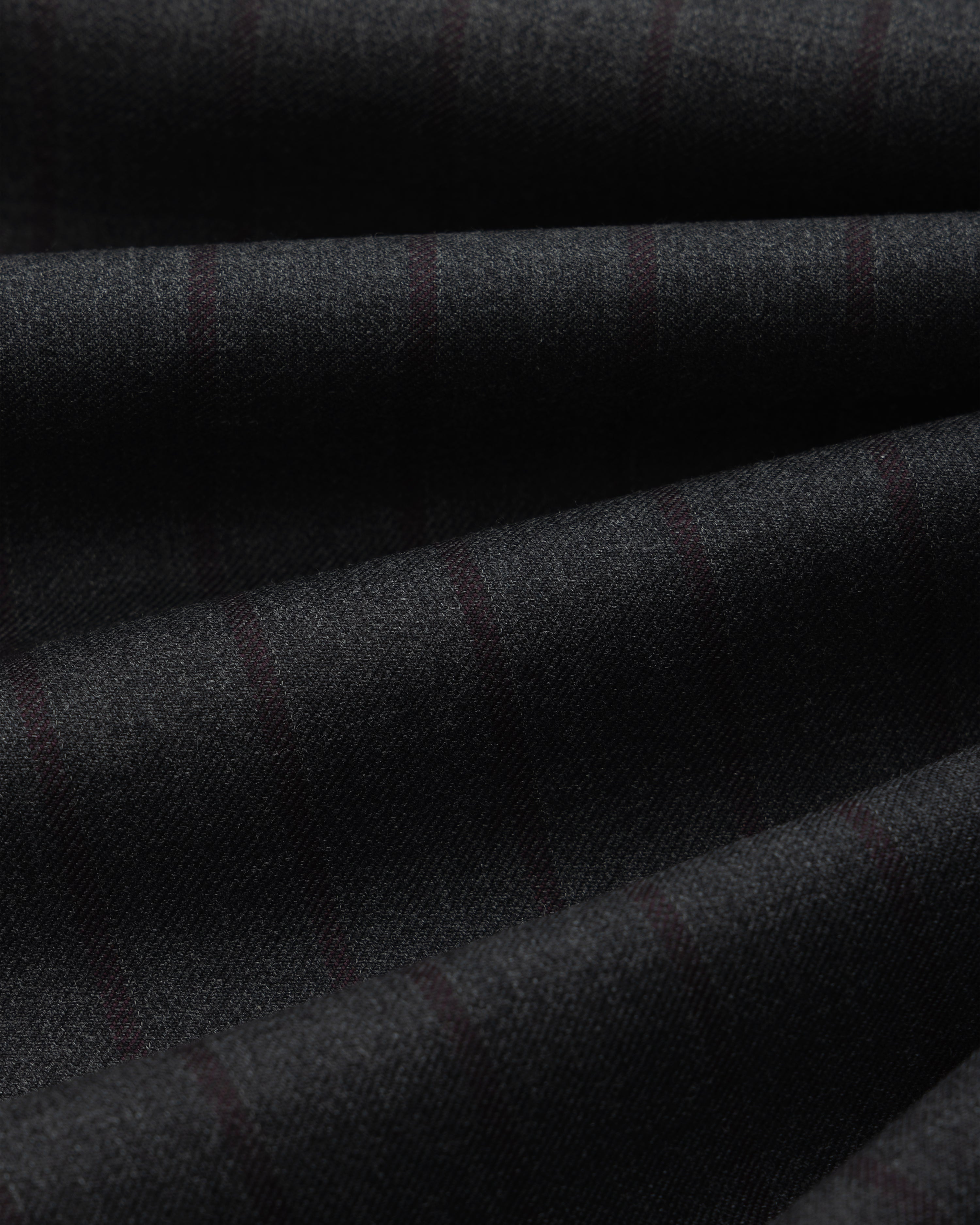 Close-up of dark grey Striped Double Pleated Suiting Trouser fabric, featuring subtle vertical pinstripes in ripples.