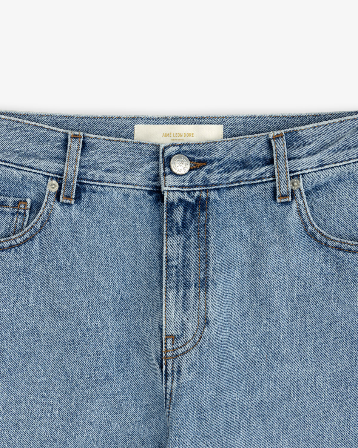 Close-up of ALD Relaxed Fit Denim light-wash blue jeans featuring a button fly and a branded waistband label.
