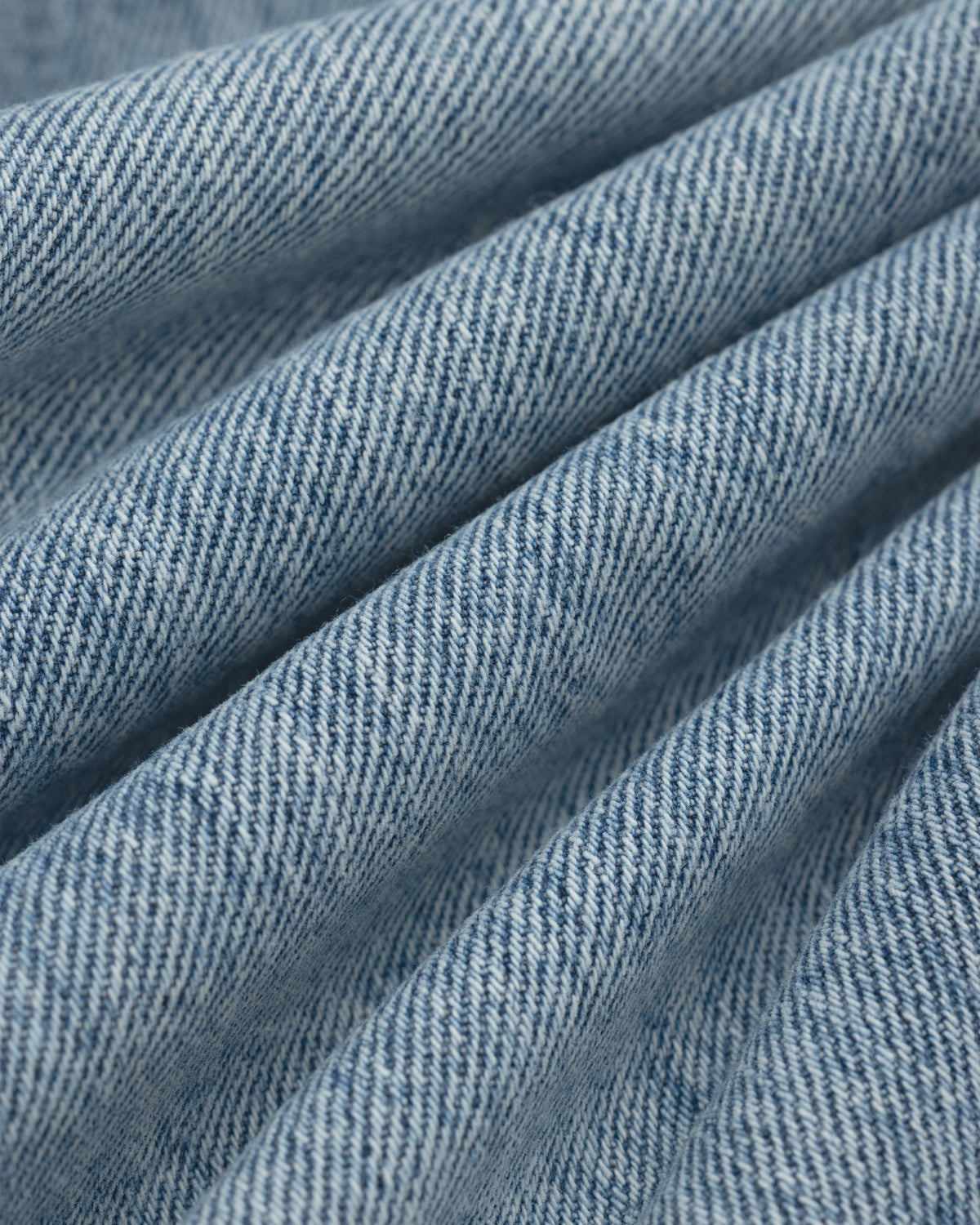 Close-up of light blue ALD Relaxed Fit Denim fabric with diagonal folds.
