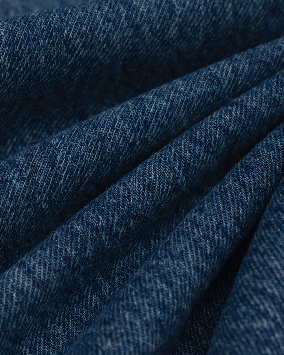 Close-up of folds in the dark blue denim fabric of the ALD Relaxed Fit Denim.
