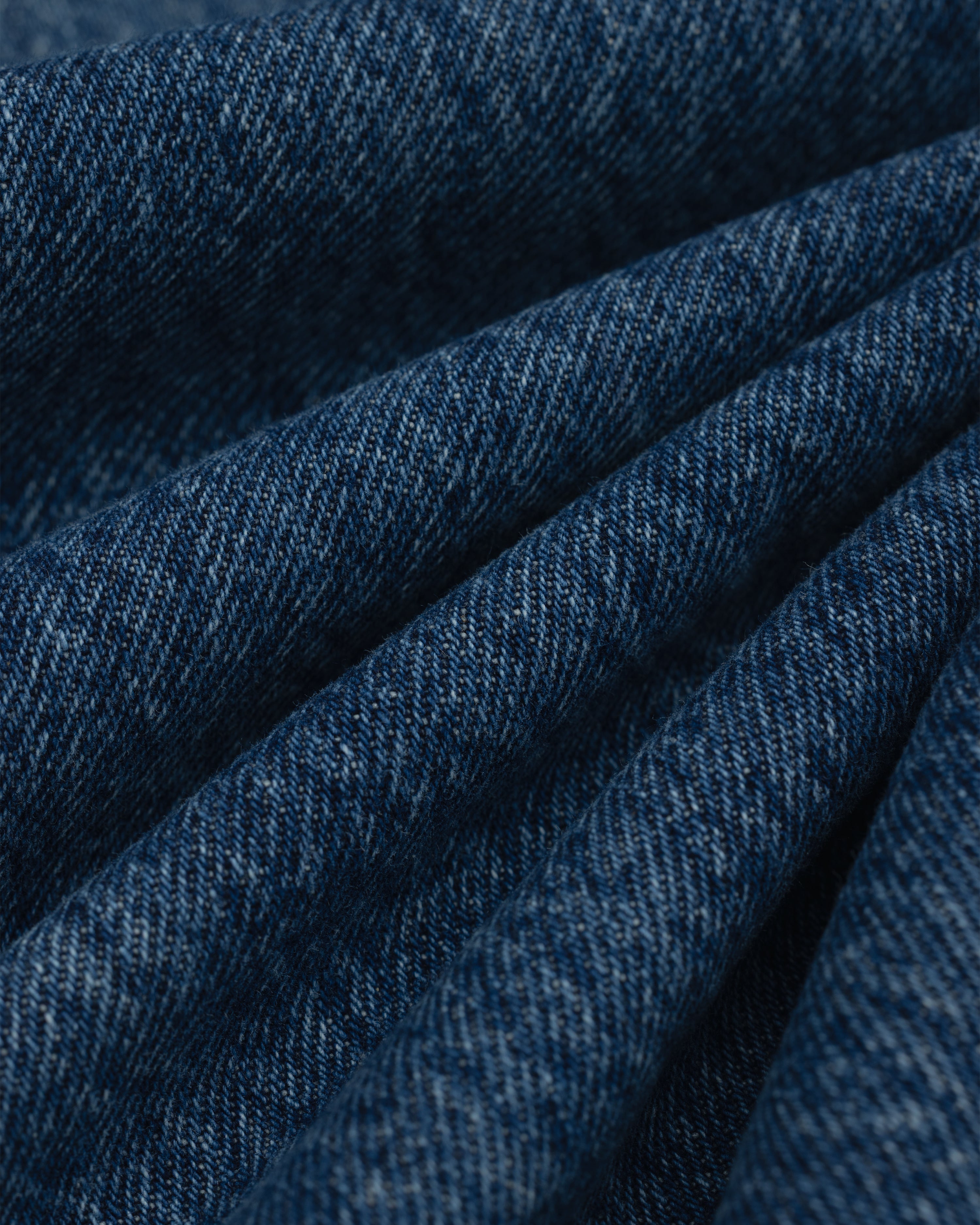 Close-up of folds in the dark blue denim fabric of the ALD Relaxed Fit Denim.
